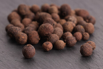natural allspice in peas on a stone gray plate
