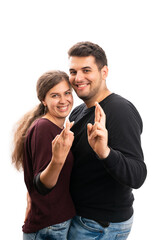 Cute adult couple making fingers crossed good luck gesture