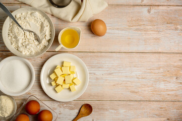 Baking ingredients, eggs, flour, butter, oil and milk. Top view, rustic wooden background, copy...