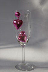 Pair of pink heart shaped earrings on the champagne glass on white background. Romantic jewelry for Valentines party.