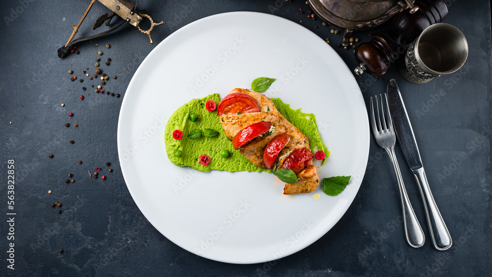 Poster chicken fillet with tomatoes and spinach puree and basil.