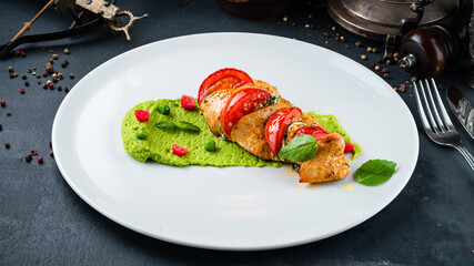 Fried chicken fillet with tomatoes and spinach puree and basil.
