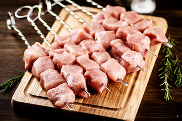 Pork kebab raw on skewers on a cutting board. 