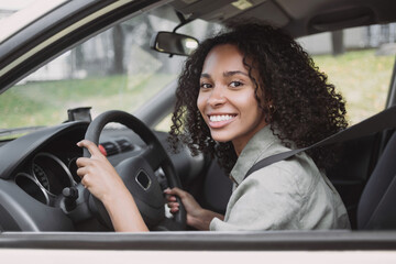 Smiling young woman driving a car. Beautiful student girl behind the wheel, transportation, car rental, credit, modern lifestyle, business concept