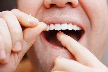 a man's mouth close-up. a man brush your teeth with dental floss. concept of hygiene and health of teeth and oral cavity. daily care and brushing of teeth.