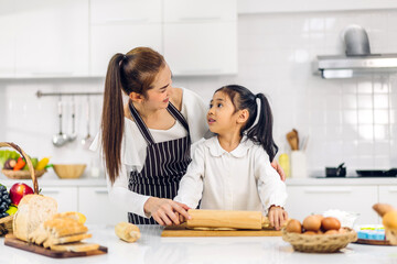 Portrait of enjoy happy love asian family mother and little toddler asian girl daughter child having fun cooking together with dough for homemade bake cookie and cake ingredient on table in kitchen