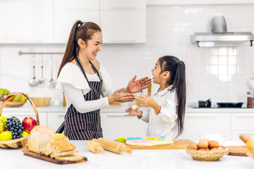 Obraz na płótnie Canvas Portrait of enjoy happy love asian family mother and little toddler asian girl daughter child having fun cooking together with dough for homemade bake cookie and cake ingredient on table in kitchen