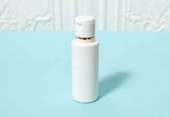 A standing white colored round bottle laying out on the top of a blue paper