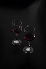 two glasses of red wine on isolated on black background