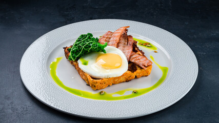 Breakfast plate waffles with fried bacon, egg, lettuce, pumpkin seeds and sauce.