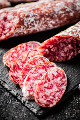 Pieces of salami sausage on a stone board. 