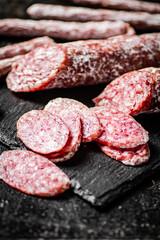 Pieces of salami sausage on a stone board. 