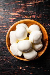 A wooden plate on a table with mozzarella. 