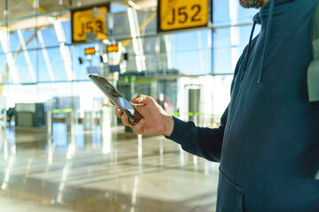 Cropped view of caucasian young man hands typing on phone at airport boarding gate