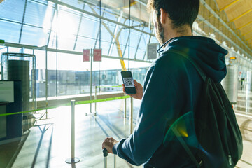 Cropped view of unrecognizable man holding qr boarding ticket on screen phone flying at airport lunge