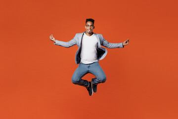Fototapeta na wymiar Full body young employee business man corporate lawyer wear formal grey suit shirt glasses work in office jump high hold spreading hands in yoga om aum gesture isolated on plain red orange background.