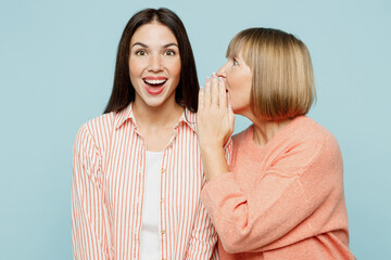 Elder parent mom with young adult daughter two women together wear casual clothes whispering gossip...