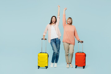 Winner elder parent mom with young adult daughter two women wear casual clothes holding bag isolated on plain blue background Tourist travel abroad in free time rest getaway. Air flight trip concept.