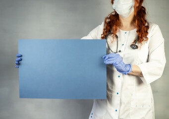 The doctor is holding a blue sheet of paper. Doctor's hand in protective gloves with a poster....