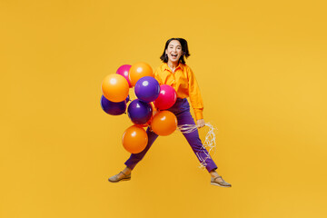 Full body happy fun cheerful young woman wearing casual clothes celebrating hold bunch of balloons look camera fooling around isolated on plain yellow background. Birthday 8 14 holiday party concept.