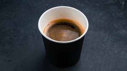Obraz na płótnie Canvas A cup of hot espresso coffee, black coffee in paper cup on dark background.