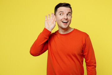 Young curious nosy fun smiling caucasian man wear orange casual clothes try to hear you overhear...