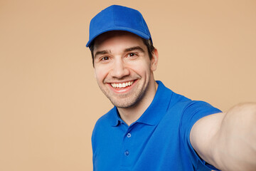 Close up delivery guy employee man wear blue cap t-shirt uniform workwear work as dealer courier doing selfie shot pov on mobile cell phone isolated on plain light beige background. Service concept.