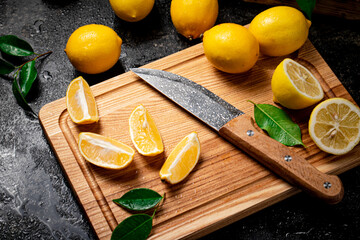 Sliced fresh lemons on a wooden cutting board with a knife. 