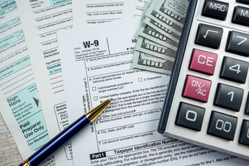 business accounting concept - 1040 tax form with pen calculator us dollar bills