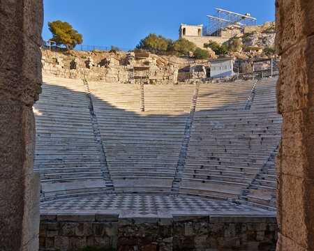 The ancient Athens temple of Nike above the stands of the conservatory of Herod Atticus, as seen through an arch. Cultural travel in Athens, Greece.