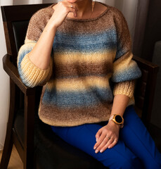 A woman poses in a knitted sweater in the interior