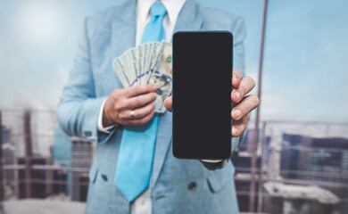 closeup businessman in blue suit holding dollar bills and smartphone with blank black screen