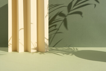 Abstract green background with shadow of palm leaves for the presentation of a cosmetic product. A scene with a geometric beige backdrop. Podium for product promotion, beauty, natural eco cosmetic.
