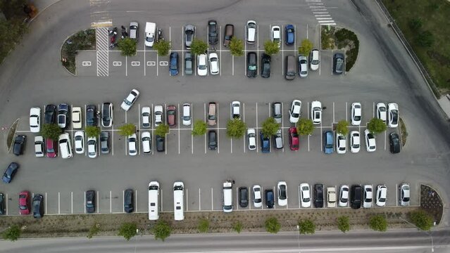 Busy large modern carpark with symmetrical roads rows of parking bays lots of symmetry and colours aerial view from drone up above looking down.