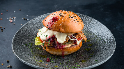 American food chicken burger with tomato, cheese, lettuce and cowberry.