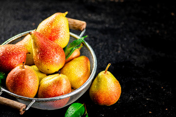 Fresh pears with leaves in a colander. 