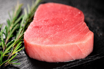Raw tuna on a stone board with rosemary. 