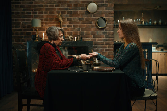Young woman at fortune teller chiromancer consultation side view shot