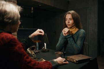 Gypsy witch reading tarot cards for young woman visitor