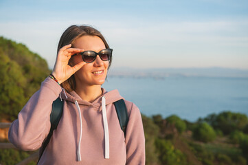 Young beautiful woman wearing eyeglasses looking on the sunlight over the sea