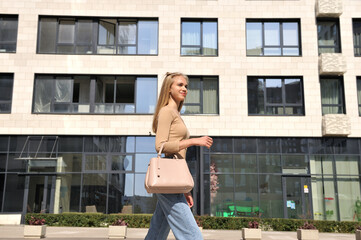 A beautiful girl with a bag walks down the street in the city