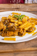 Piatto di pasta con sugo di genovese napoletana con carne e cipolle guarnito con formaggio grattugiato e basilico fresco servito in un ristorante napoletano