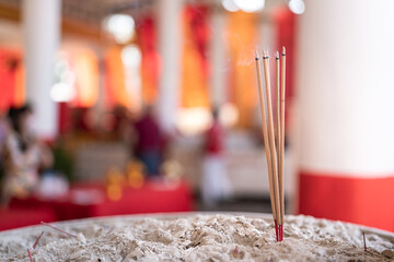 Group of incense are sticking on the ash pot after pay homage at the temple in Chinese new year event. Close-up and selective focus.