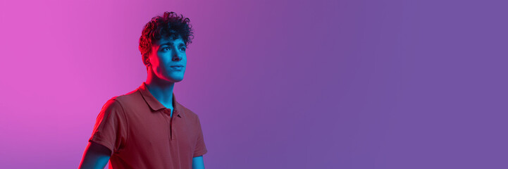 Horizontal banner with portrait of young man over background in neon light. Beauty, fashion, youth concept.