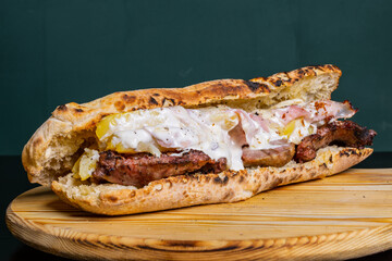 Panuozzo napoletano cotto al forno e ripieno di salsiccia grigliata, patate al forno, prosciutto cotto e formaggio fuso servito in una pizzeria napoletana