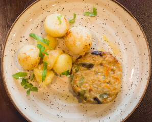 chicken burger with boiled potatoes on plate. top view