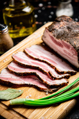 Pieces of pork lard on a cutting board with green onions and bay leaves. 