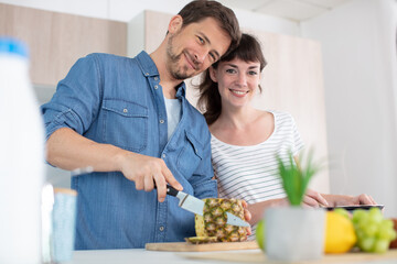 Obraz na płótnie Canvas smiling couple preparing fruit in the kitchen