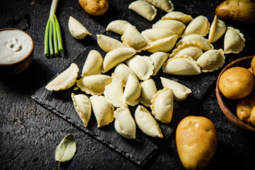 Potato dumplings on a stone board with sour cream and green onions. 