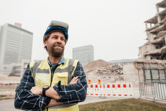 Thoughtful worker with VR glasses standing at construction site